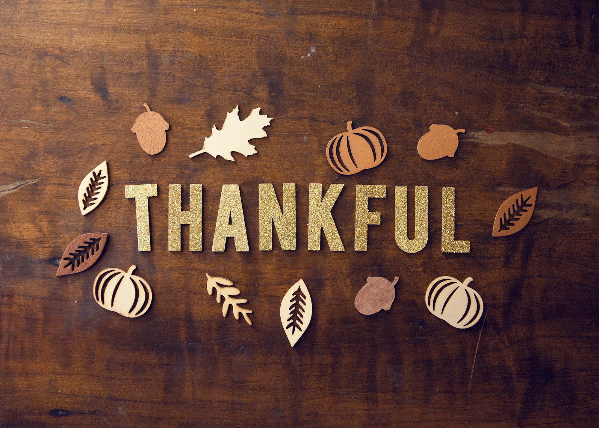 Wooden table with decorative leaves and the word "thankful".